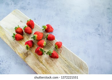 Freshly Picked Strawberries On Wooden Chopping Board Over Concrete Bench, Top View