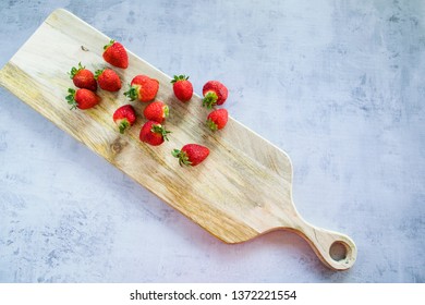 Freshly Picked Strawberries On Wooden Chopping Board Over Concrete Bench, Top View