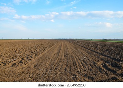 Freshly Plowed Field Ready For Seeding And Planting In Spring.  Farmland. Empty Plowed Farm Land Prepared For The New Crop. Agriculture. Brown Black Soil Near Village.