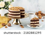 Freshly prepared delicious chocolate cake with walnuts on a white table on a cake stand