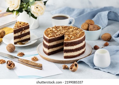 Freshly prepared delicious chocolate cake with walnuts on a white table on a cake stand