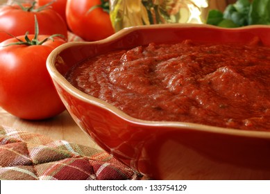 Freshly Prepared Pasta Or Pizza Sauce In Decorative Bowl With Tomatoes, Olive Oil, And Herbs In Background. Closeup With Shallow Dof.