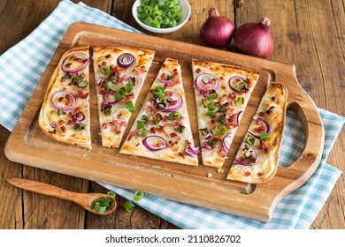 freshly prepared tarte flambée on wooden board - Shutterstock ID 2110826702