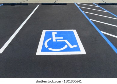 Freshly resurfaced and repainted handicap parking space in a parking lot. The number of handicap spaces increases with the size of the lot, requiring roughly one handicapped spot per 25 spaces.