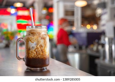 Freshly Served Iced Latte Coffee Drink In A Jar, On Cafe Diner Counter, With Mocha Syrup Cream Swirl