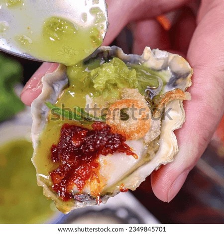 Freshly shucked oysters, delicately arranged on a bed of crushed ice, accompanied by a tantalizing seafood sauce that adds a burst of complementary flavors, enhancing the briny and succulent taste