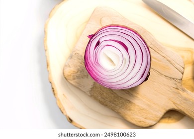 A freshly sliced red onion placed on a wooden cutting board - Powered by Shutterstock