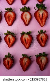 Freshly sliced strawberries in rows on pink tray food knolling