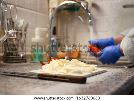 Freshly sliced white onions on a cutting board, against a background of washing vegetables. Healthy food, natural, vegetarian products. Cooking vegetables at home.