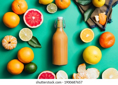 Freshly Squeezed Citrus Juice In Reusable Bottle With Fresh Fruits On Green Kitchen Table Top View