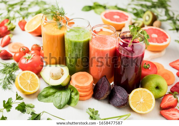 freshly\
squeezed juice, fruit and vegetable smoothies in glass glasses on a\
white table decorated with a composition of\
fruit