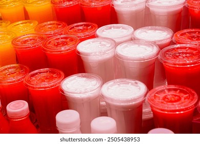 Freshly squeezed juices of various fruits in transparent plastic cups at a market stall, fresh juices in the fruit store - Powered by Shutterstock