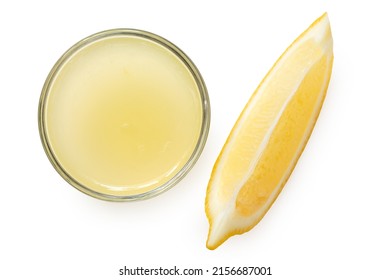 Jugo de limón recién exprimido en un recipiente de vidrio al lado del segmento de limón aislado sobre blanco. Vista superior.