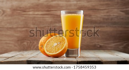 Freshly squeezed orange juice in a high glass on wooden background. Roustic scene, fresh fruit drink