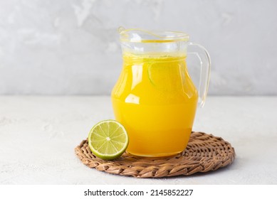 Freshly squeezed orange juice with ice and lime slices in a jug on the table.