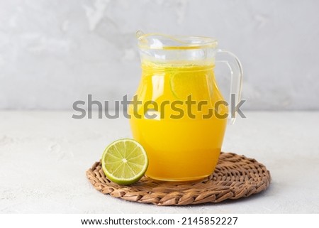 Freshly squeezed orange juice with ice and lime slices in a jug on the table. Foto stock © 