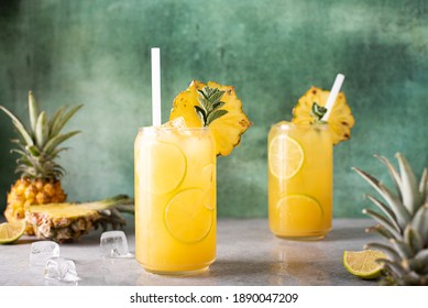 freshly squeezed pineapple juice with lime wedges and ice in glass jars