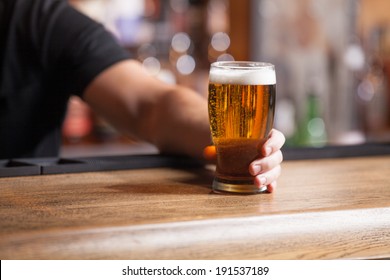 Freshly tapped beer. Bartender holding a freshly tapped glass of beer in his hand - Powered by Shutterstock