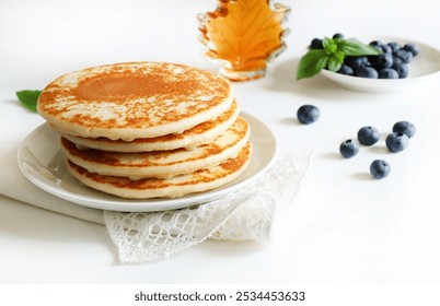 Freshly tasty stack of pancakes on the plate, maple syrup and blueberries isolated on a white background. Delicious homemade breakfast or lunch. Directly above.