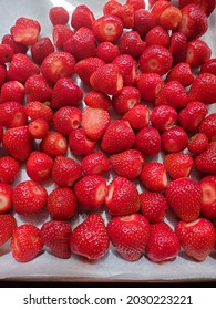 Freshly washed and hulled strawberries are on a baking tray ready to be frozen.