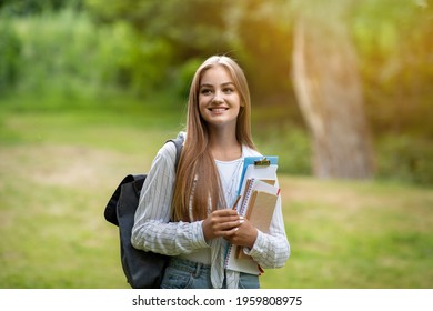 Freshman Girl. Portrait Of Beautiful Female College Student With Workbooks And Backpack Posing Outdoors At Campus Yard, Copy Space