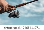 Freshwater fishing in summer. Spinning reel on a spinning rod in the hands of a fisherman.