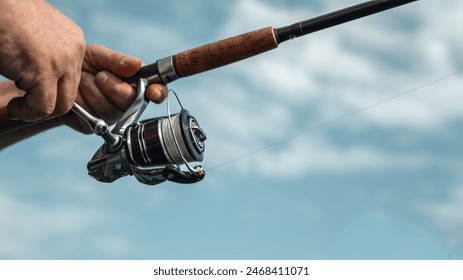 Freshwater fishing in summer. Spinning reel on a spinning rod in the hands of a fisherman. - Powered by Shutterstock