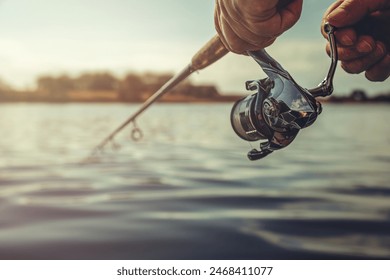 Freshwater fishing in summer. Spinning reel on a spinning rod in the hands of a fisherman. - Powered by Shutterstock