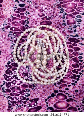 Freshwater pearls on a pink background. Snake skin pattern on fabric.