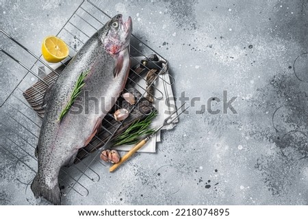 Freshwater trout, fresh raw fish on a grill ready for cooking. Gray background. Top view. Free space for your text.