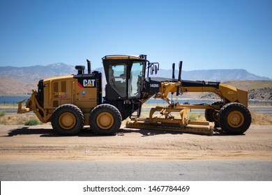 Fresno, California / USA - June 29 2019: CAT Caterpillar 140M2 Motor Grader by the side of the road with mountains in background