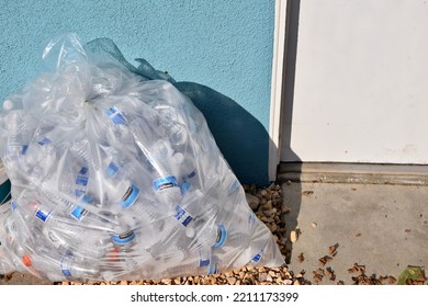 FRESNO, UNITED STATES - Jan 19, 2022: A Clear Bag Full Of Empty Water Bottles On The Ground Against A Blue Wall Outside