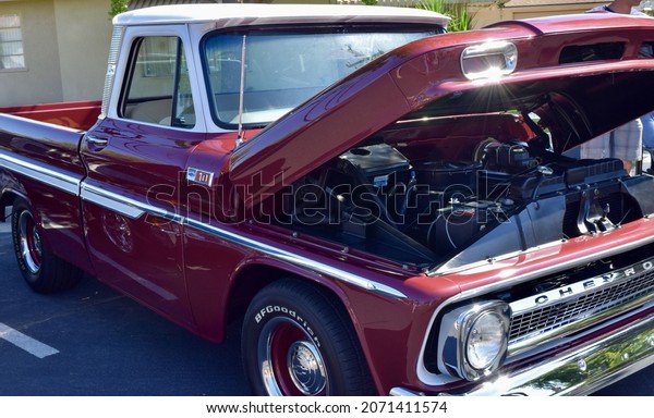 FRESNO, UNITED STATES - Oct 09, 2021: A closeup of a\
Wine Colored 1965 Classic C-10 Chevy Pickup Truck and white top\
with hood up