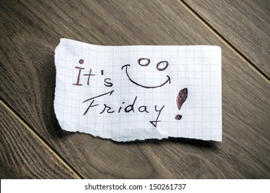 It's Friday - Hand writing text on a piece of paper on wood background
