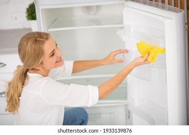 Fridge Cleaning .Blonde Housewife In White Shirt Cleaning The Fridge
