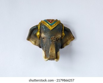 Fridge Magnet Souvenir In Shape Of One Decorated Brown Elephant Head Isolated On White Background. Travel To Thailand Concept. Top View Flat Lay Close Up, Copy Space