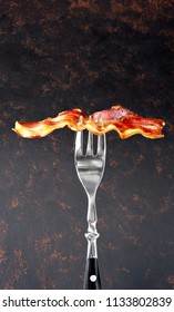 Fried Bacon On Fork. Front View, Isolated On Black Background.