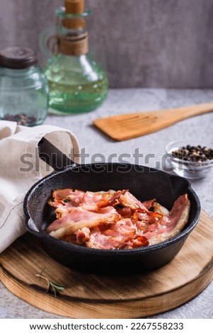 Fried bacon in a pan ready for dinner on the table. Vertical view