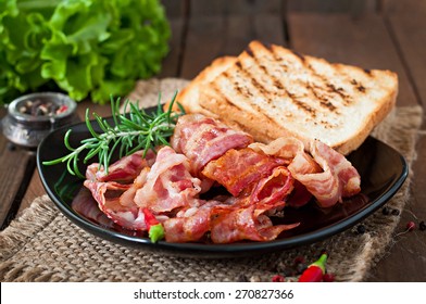 Fried Bacon And Toast On A Black Plate On A Wooden Background