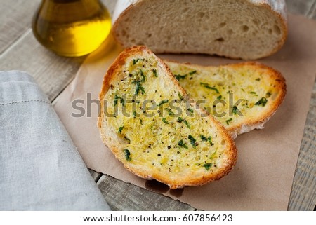 Fried bread with olive oil, garlic and herbs on a wooden table. Rustic style.
