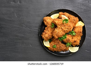 Fried Breaded Chicken Wings On Plate Over Black Background With Copy Space. Top View, Flat Lay