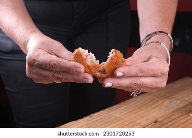 Fried and breaded cod fritters, fish empanadas, cod fritters, Brazilian style cod fritters, disc of meat opened by a female hand - Shutterstock ID 2301720253