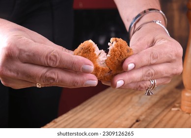 Fried and breaded cod fritters, fish empanadas, cod fritters, Brazilian style cod fritters, disc of meat opened by a female hand - Shutterstock ID 2309126265