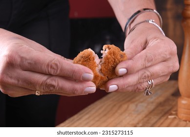 Fried and breaded cod fritters, fish empanadas, cod fritters, Brazilian style cod fritters, disc of meat opened by a female hand - Shutterstock ID 2315273115