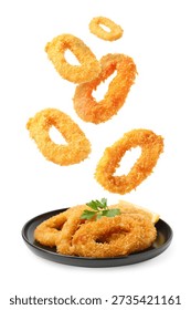 Fried breaded squid rings falling onto plate against white background