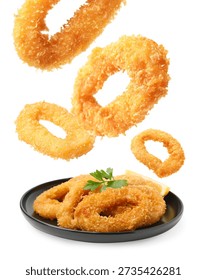 Fried breaded squid rings falling onto plate against white background