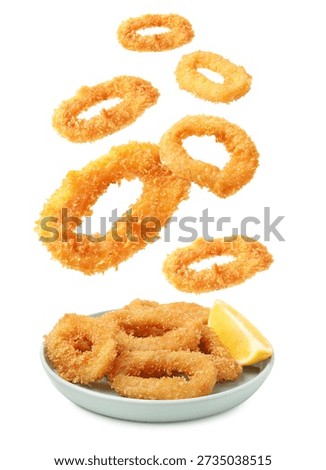 Fried breaded squid rings falling onto plate against white background