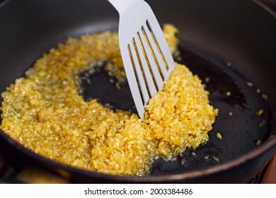 Fried Bulgur In A Frying Pan. Caramel Flavored Wheat Grains Stirring With A Kitchen Spatula In Boiling Oil