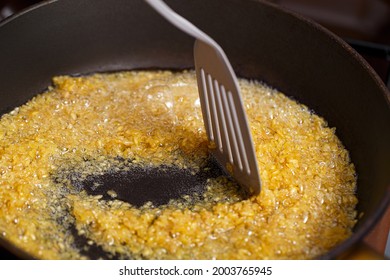 Fried Bulgur In A Frying Pan. Caramel Flavored Wheat Grains Stirring With A Kitchen Spatula In Boiling Oil