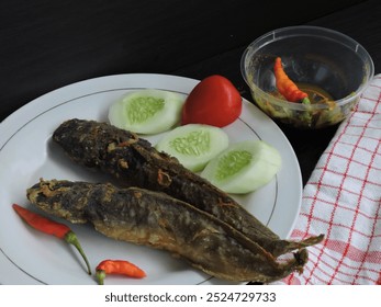 fried catfish covered in thin flour mixed with herbs and spices, served on a white plate with a dark background - Powered by Shutterstock